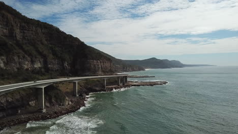 Antena:-Vehículos-No-Tripulados-Que-Siguen-A-Los-Vehículos-Que-Conducen-A-Través-De-Un-Gran-Puente-A-Lo-Largo-De-Una-Hermosa-Costa,-En-Nueva-Gales-Del-Sur,-Australia