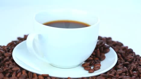 Tasse-Kaffee,-Umgeben-Von-Kaffeebohnen,-Die-Sich-Drehen