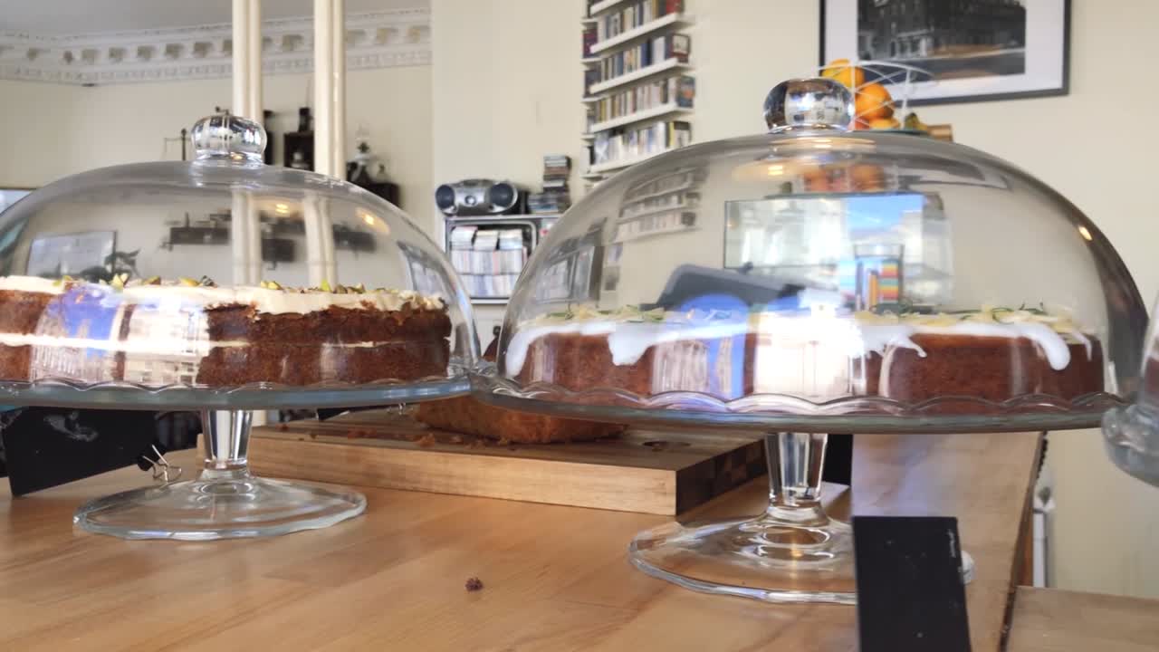 A panning shot of delicious gluten free cakes in cake display domes, at a local coffee shop | Gourmet Coffee House | Shot in HD at cinematic 24 fps