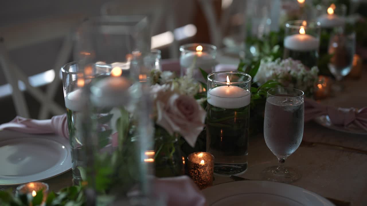 bella sistemazione lungo tavolo per un ricevimento di nozze, adornato con candele delicate, fiori freschi, e tutti i dettagli che contribuiscono ad un ambiente romantico e elegante