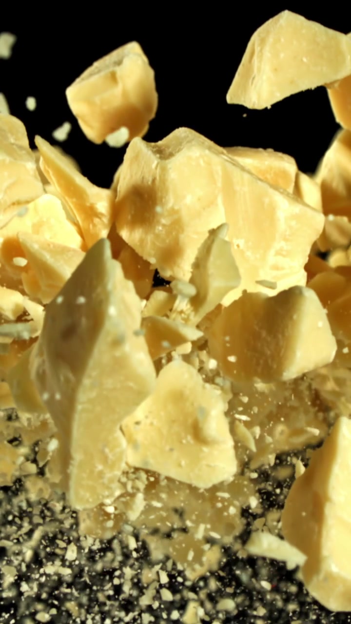 Hvide chokoladestykker falder i slowmotion på sort baggrund