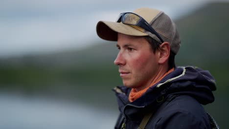 hombre joven atractivo en ropa de pesca deportiva al aire libre, retrato lateral