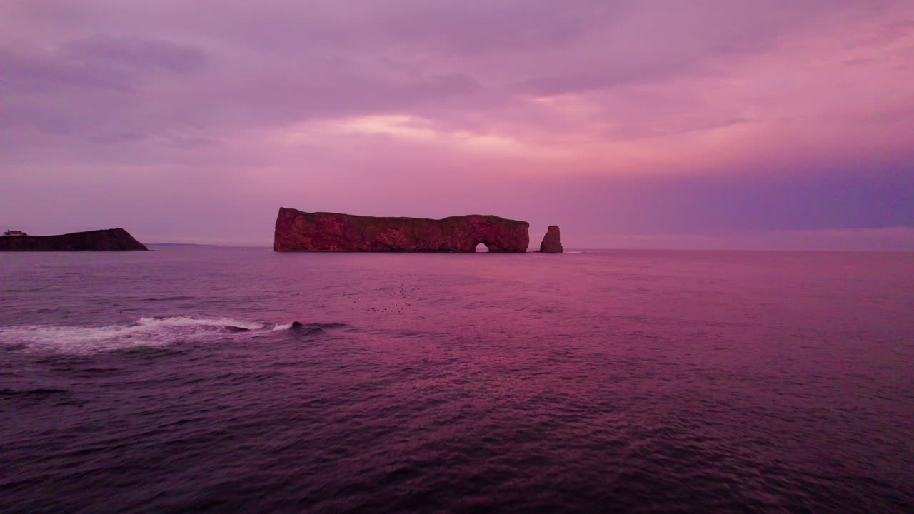 vista de avión no tripulado retrocediendo de la roca de percé durante una puesta de sol nublada sobre el río san lorenzo