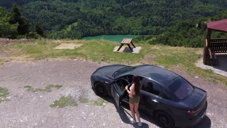 woman getting off the car and walks toward viewing point overlooking lake plastiras in karditsa, greece