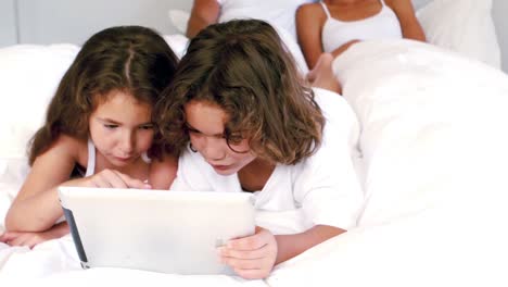 hermanos lindos usando tableta en la cama de sus padres