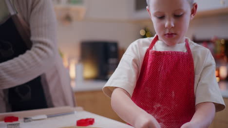 hornear galletas cerca de la mano de un niño cortando galletas en la masa