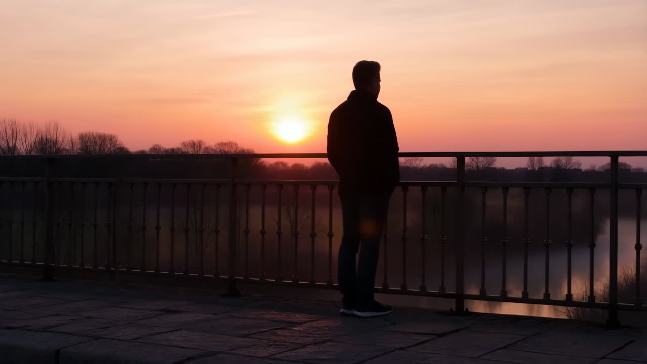 Man silhouetted against a beautiful sunset on a bridge