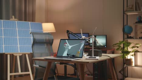 laptop showing wind turbine on the table next to the solar cell at the office