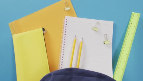 video of school supplies, notebook, pens, ruler, paper clips over blue background