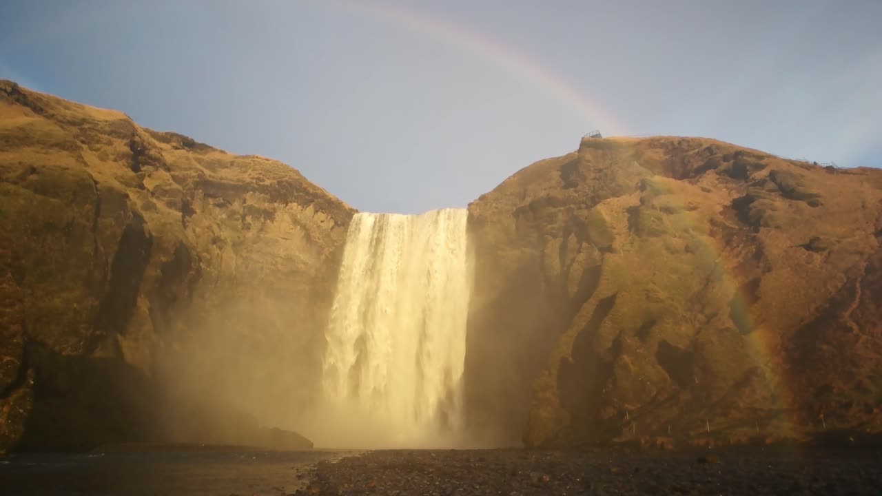 la cascada de seljalandsfoss en cámara lenta con un arco iris en la parte superior.