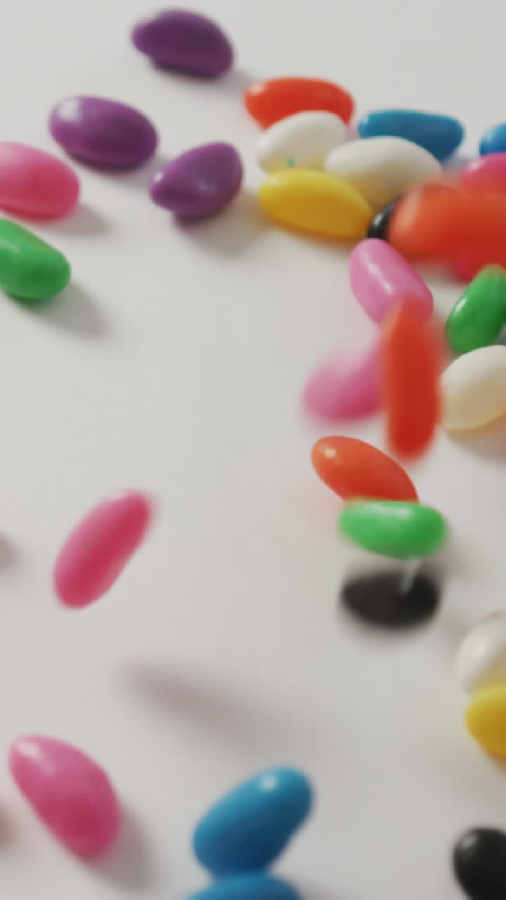 Video en primer plano de dulces multicolores cayendo sobre fondo blanco.