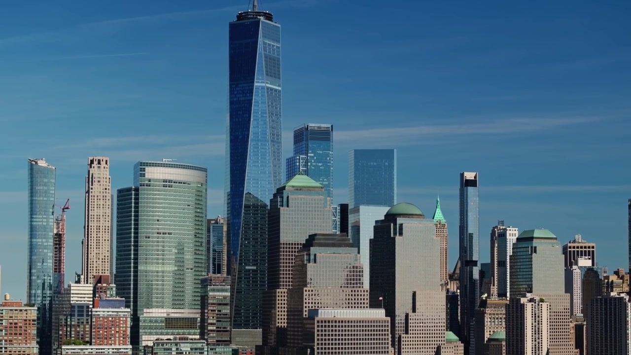 Drone em movimentos de trucking, pan e tilt para mostrar o topo dos edifícios no horizonte da cidade de Nova York acima do Rio Hudson
