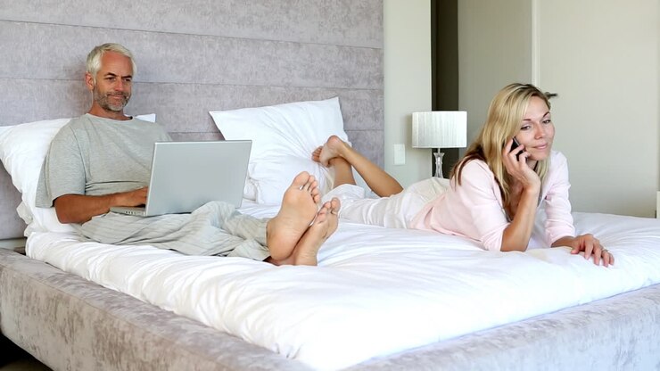 Woman on the phone as man is using laptop behind her