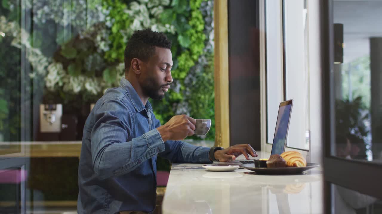 African american businessman using laptop drinking coffee in cafe