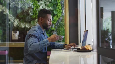 Empresario-Afroamericano-Usando-Una-Computadora-Portátil-Tomando-Café-En-La-Cafetería
