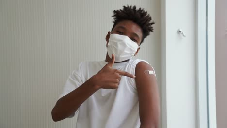 african american teenager showing covid-19 vaccine bandage merrily