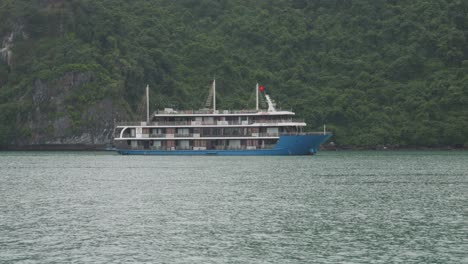 Blaues-Kreuzfahrtschiff-Auf-Grünem-Inselhintergrund-In-Der-Halong-Bucht,-Nordostvietnam