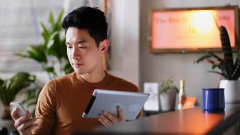 man using digital tablet and mobile phone on kitchen counter 4k