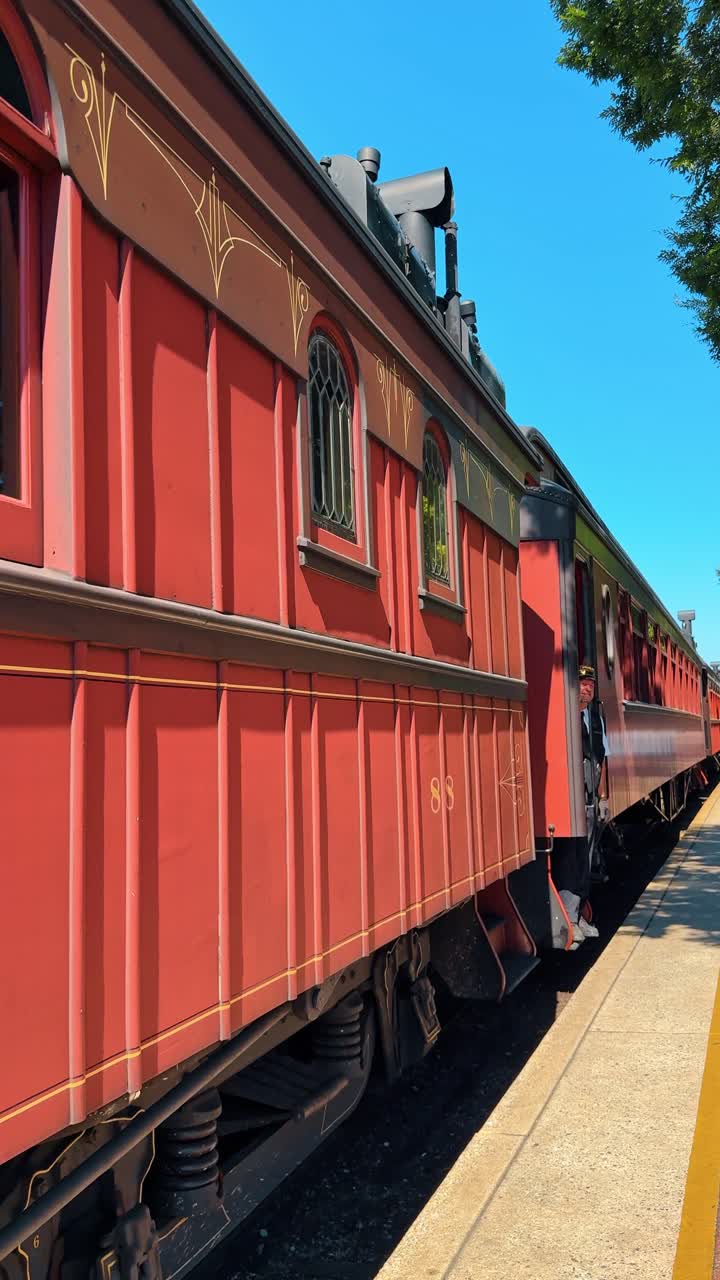 Boston, USA, 8 maggio 2025: Vagone passeggeri in legno rosso vintage di nome Marian in stazione. Prospettiva laterale di una carrozza passeggeri rossa di nome Marian parcheggiata su una piattaforma di cemento sotto un cielo blu chiaro.