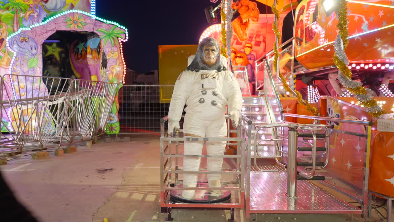 Person interacting with a gorilla-astronaut costume at a funfair at night