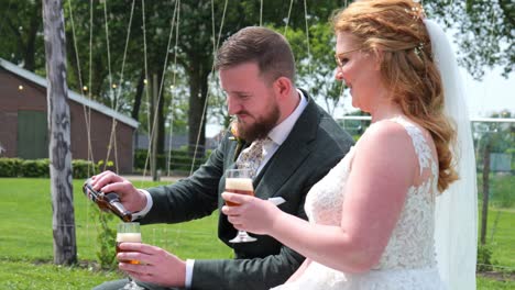 bride and groom celebrating with drinks outdoors on a sunny day