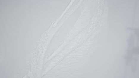 Looking-down-on-ski-tracks-in-freshly-fallen-powder-snow,-handheld