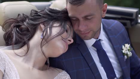 la novia bonita se apoya en el prometido en el coche cámara lenta vista de cerca