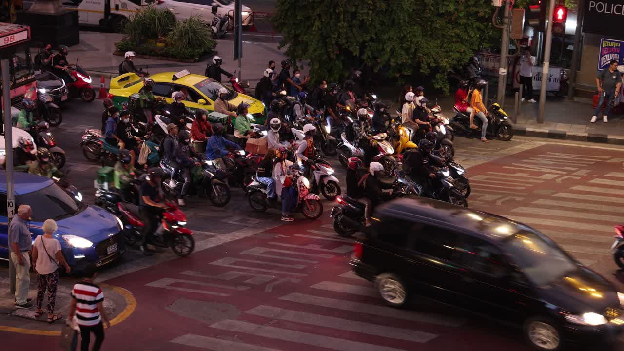 Motorcycles and cars navigate crowded city crossroads
