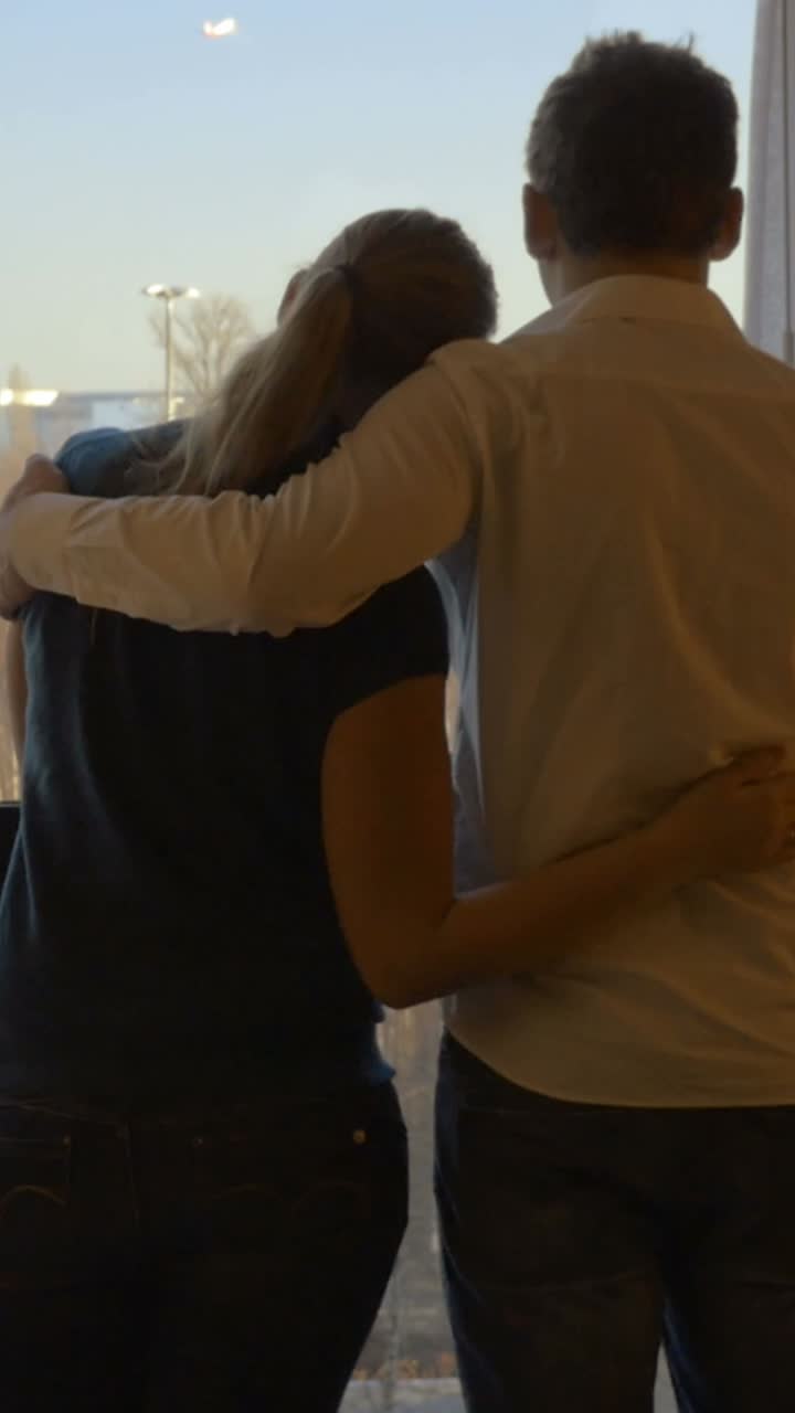 Couple Embracing and Looking Out the Window