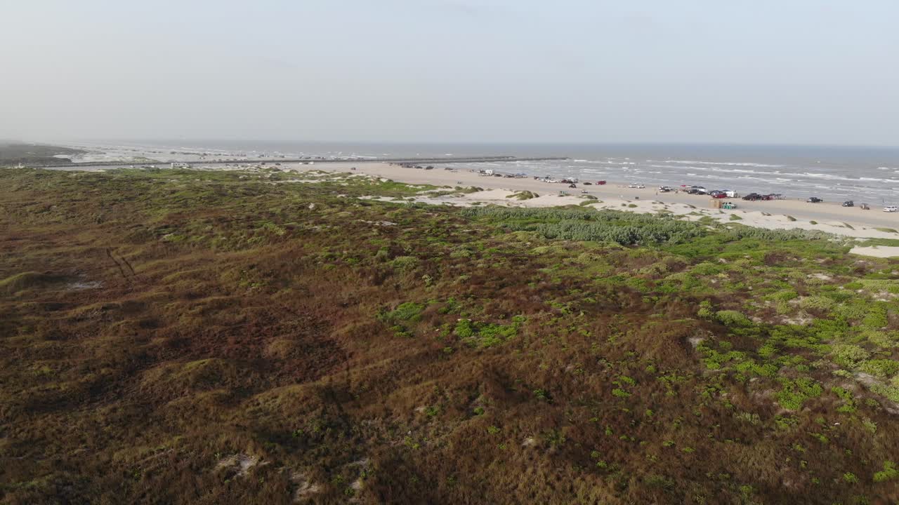 Taking off rising over the grasslands to reveal beach and jetty; finally panning left. Aerial footage of the North Packery Channel Jetty in Corpus Christi TX