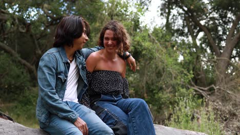 a hispanic couple sits in a park laughing and enjoying each others company