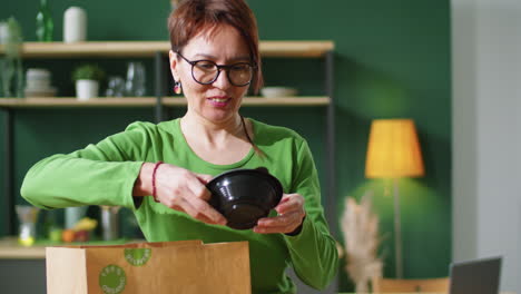 mujer quitando alimentos y bebidas ecológicos de una bolsa de papel