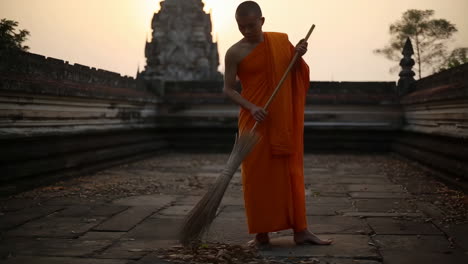 buddhist monk sweeping ancient temple grounds at golden hour
