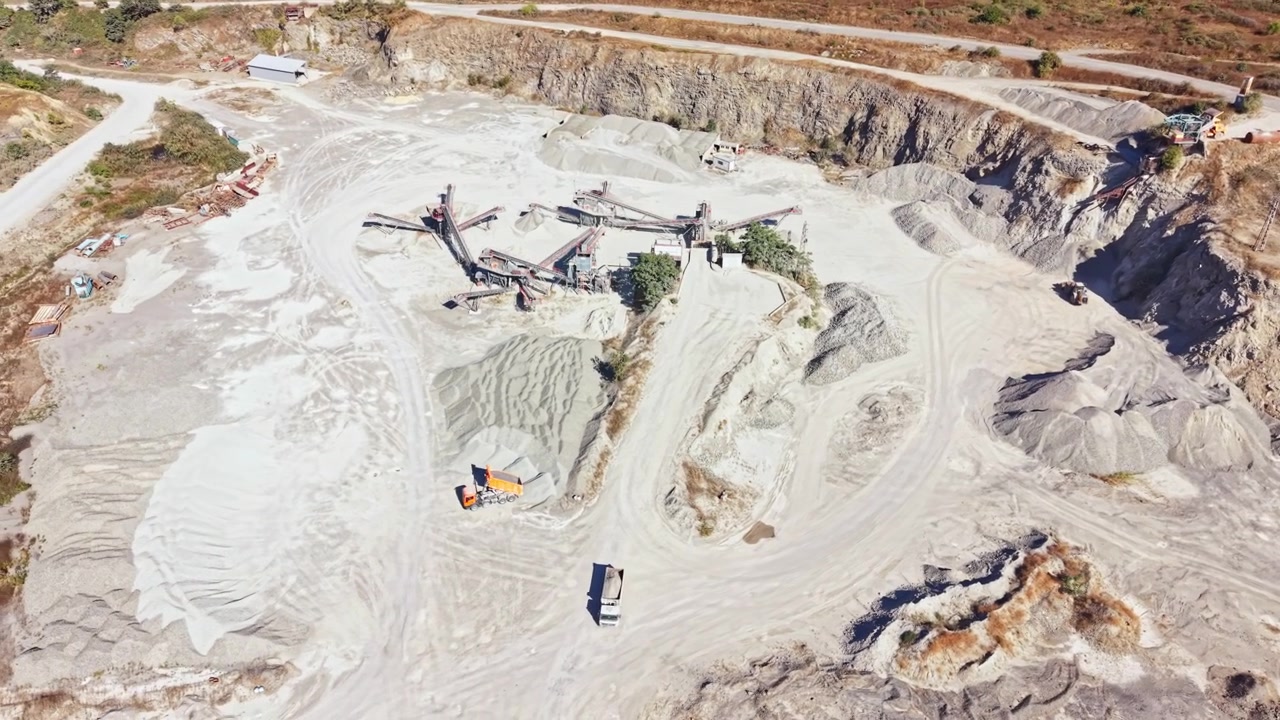 Granite quarry operations showing machines, stone piles, and roads in a large open area during daylight hours