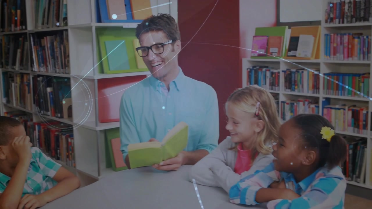 Leraar opent een groen boek en leest een verhaal voor aan kinderen aan een tafel in de bibliotheek, waarbij de leerlingen worden betrokken.