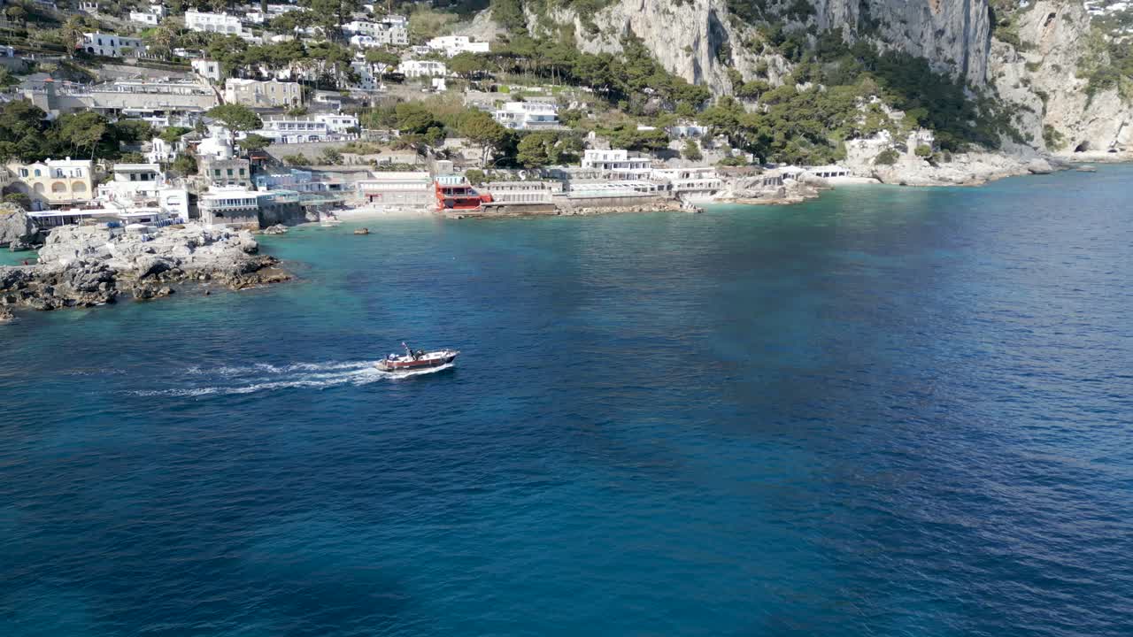 imágenes de drones de un barco a motor dejando una pequeña bahía en capri, italia