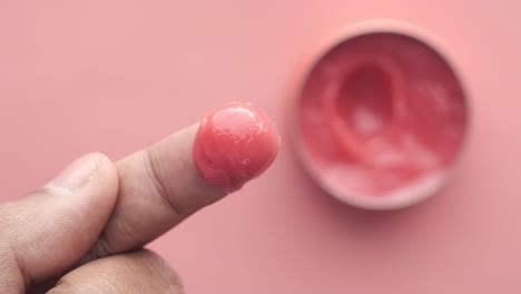 primer plano de un dedo con una gota de bálsamo para los labios rojo