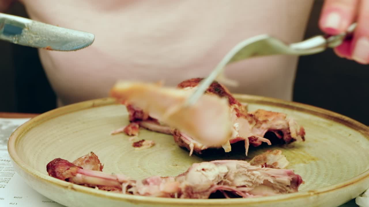 Woman cutting up a piece of grilled chicken with potatoes at a restaurant