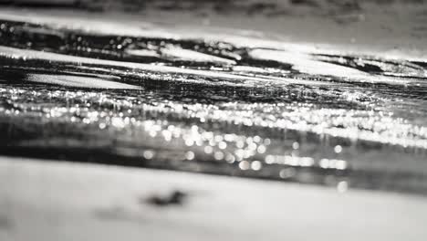 water flows slowly over the sand in a close-up shot