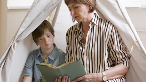 young girl with down syndrome learning to read next to her mother at home