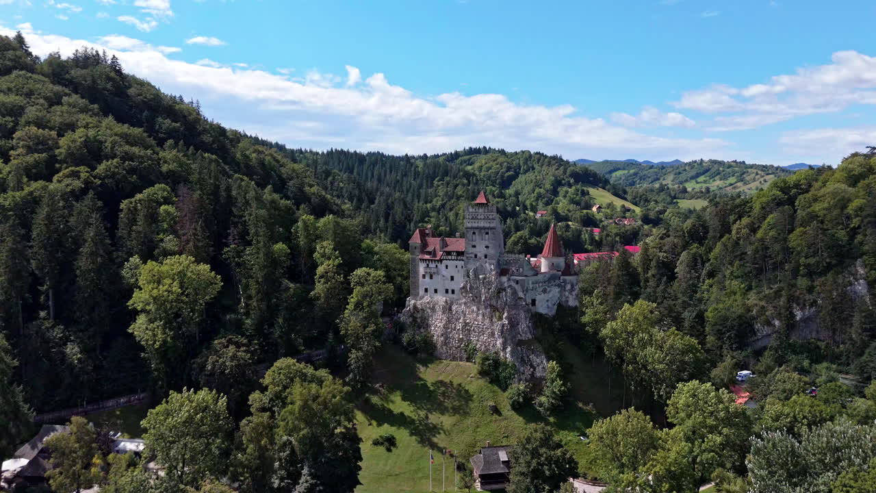Bran Castle nestled in lush green hills of Transylvania under clear skies
