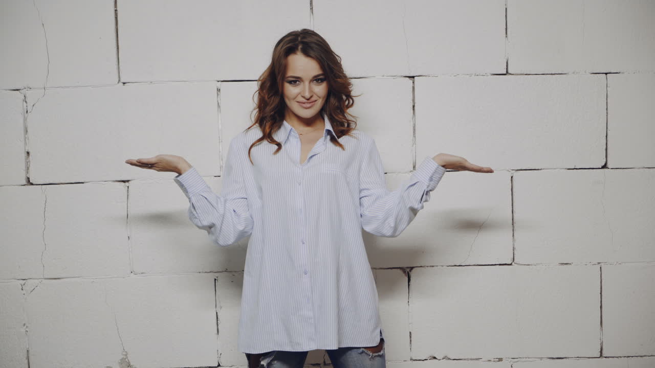 Woman in a blue shirt posing in front of a brick wall
