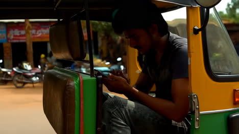 man using a smartphone in an auto-rickshaw