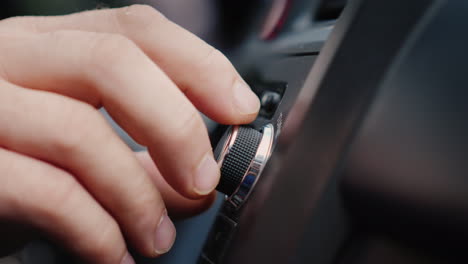 mano masculina ajusta la afinación de la toma de primer plano de la radio del coche