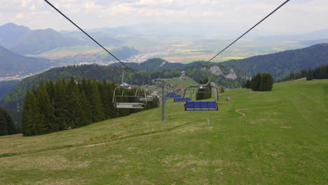 malinô brdo bike and ski resort, ružomberok, liptov, slovakia - view of empty skilift chairs over grassy hilly field in summertime