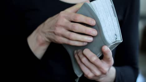 woman-praying-with-bible-on-grey-background-with-people-stock-video