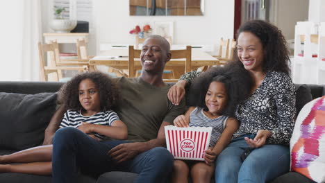 Familie-Sitzt-Zu-Hause-Auf-Dem-Sofa,-Isst-Popcorn-Und-Schaut-Gemeinsam-Einen-Film