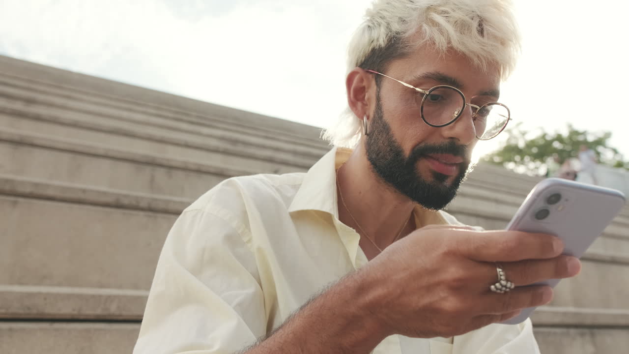 Ragazzo sorridente che usa lo smartphone all'aperto in una giornata di sole