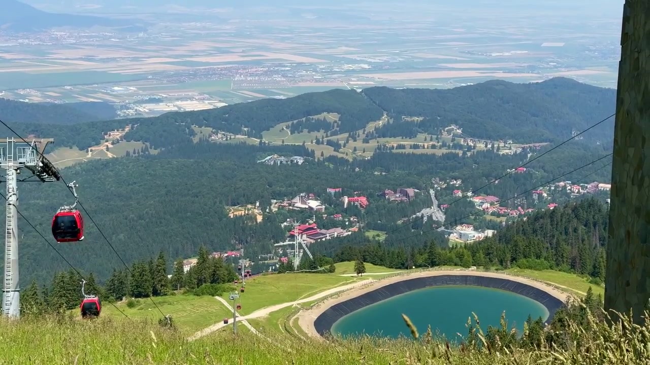 Yaz aylarında çalışan Ruia telesiyeji ile Postavaru Dağı'nın geniş panoramik çekimi. Uzakta yemyeşil alp manzarasıyla çevrili birikinti gölü görülebilir.