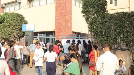 large crowd of people waiting outside gate 2 for exam results